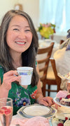 Woman holding a teacup and smiling at a tea party.