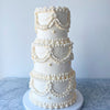 Decorative white cake with intricate designs on a marble surface.