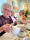 Elderly woman pouring tea at a tea party.