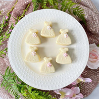White dress petit fours decorated with pastel flowers on white plate.
