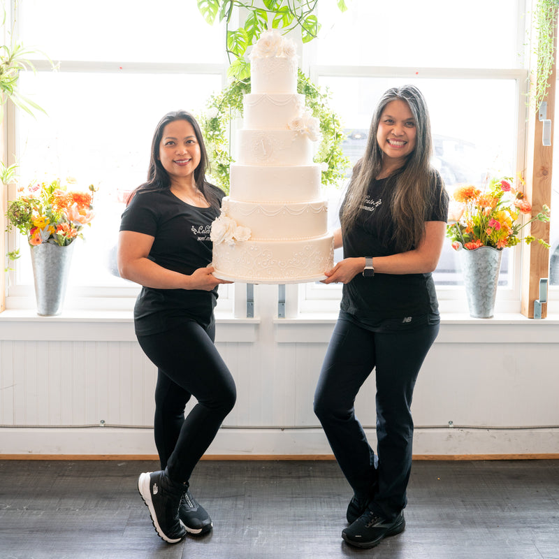 Odette and Mary Ann holding a multi-tiered wedding cake