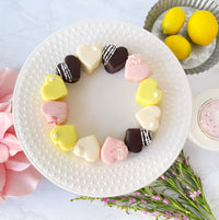 Circle arrangement of heart-shaped petit fours on white plate with lemons.