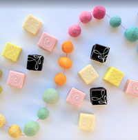 Pastel petit fours scattered among colorful candy beads.