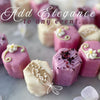 Purple and white floral-themed petit fours with delicate sugar flowers.
