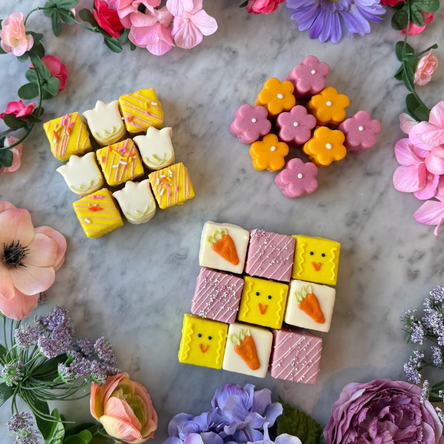 Easter petit fours bundle featuring tulip cakes, daisy cakes, and chick carrot tea cakes from a Tacoma bakery arranged with spring flowers.