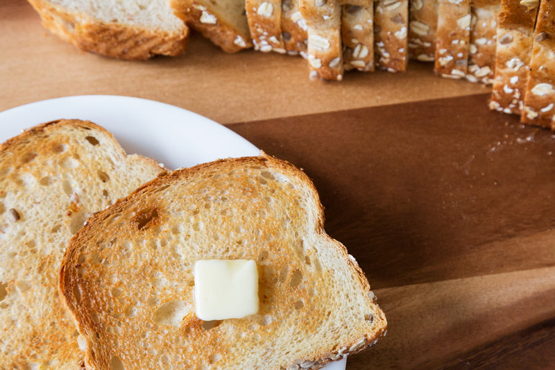 a slice of toasted bread with a knob of butter on a table